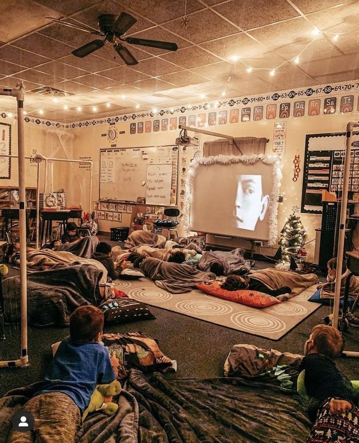 a room filled with lots of people laying on the floor and watching tv in front of them