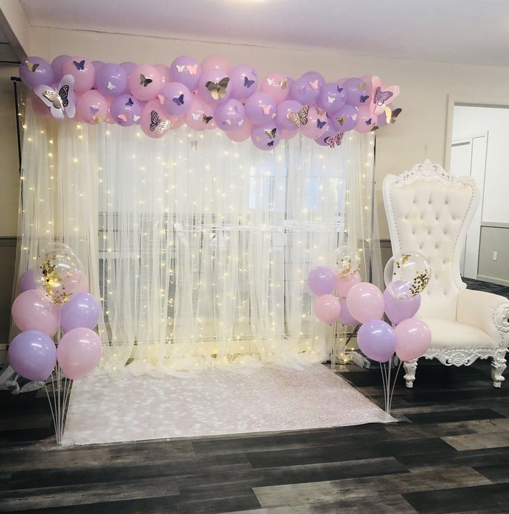 a room decorated with balloons, chairs and a white chair in front of a window