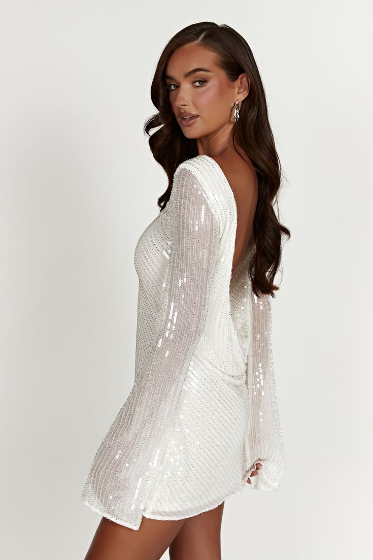 We recommend sizing down in this style. It might be love. The NALA Sequin Mini Dress was designed to be the perfect second-dress for dance-floor-loving brides. It has been crafted from our custom sequinned and beaded fabrication that shines bright in the light. The back features a low cowl to give it extra drama. Wear with our Caitlin Diamante Rope Heels to complete the look. FEATURES: High neckline Low cowl back Lined body Mini length FIT, FABRIC & CARE: Natalie is 173cm/5'8 and wears a size S; Disco White Outfit, Embellished Backless Sequin Dress For Wedding, Backless Embellished Sequin Dress For Wedding, Glamorous Contrast Sequin Wedding Gown, Glamorous Wedding Gown With Contrast Sequin, Glamorous Wedding Dress With Contrast Sequin, Glamorous White Sequin Dress With Contrast Sequins, White Glamorous Sequin Dress For Prom, White Glamorous Sequin Dress For Prom Season