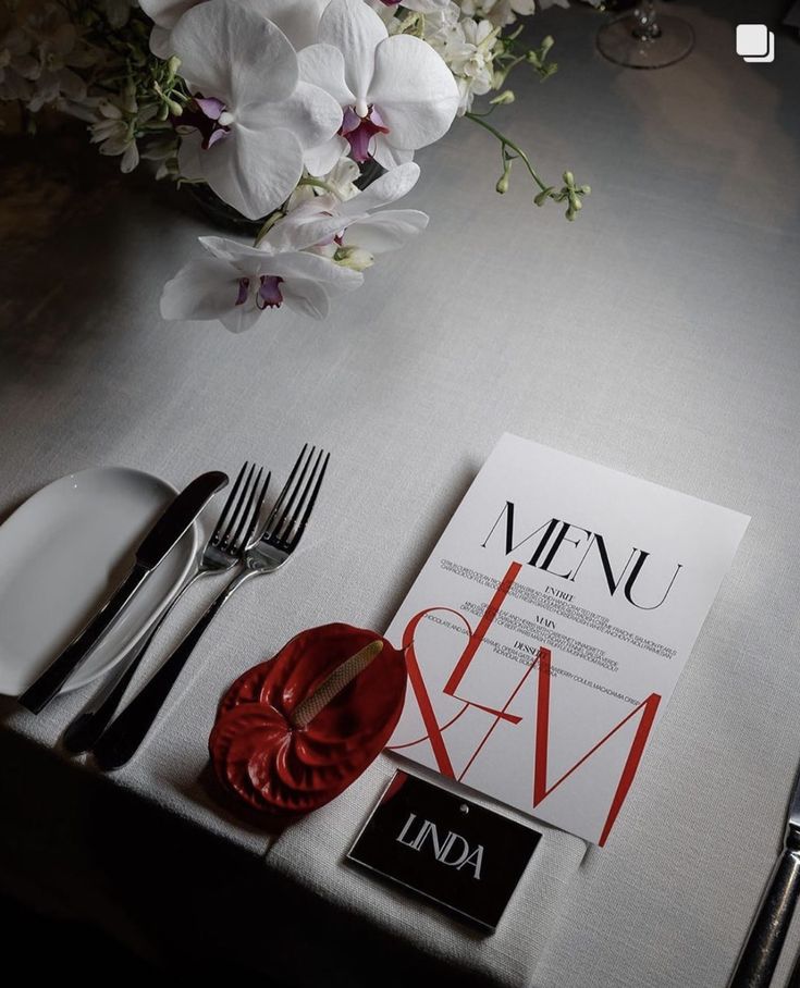 the table is set with silverware and white flowers