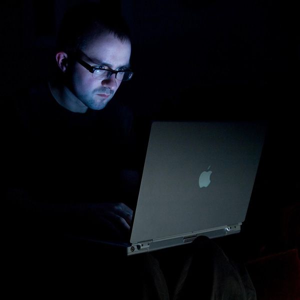 a man sitting in the dark using a laptop computer