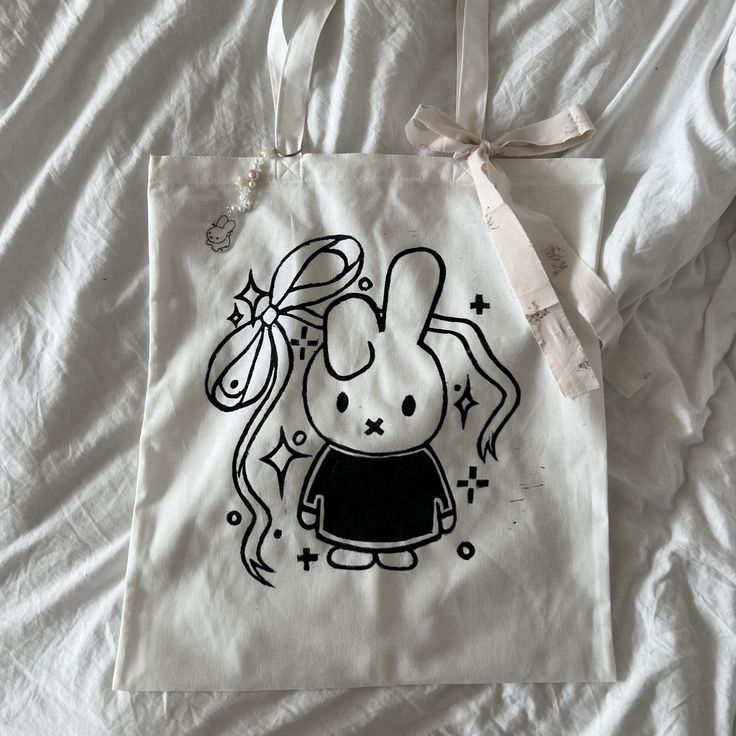 This is a my new miffy coquette tote bag design!!  Since it is handmade + block-printed these totes have some flaws, including some ink that went outside of the design. I love the miffy + the ribbons so so much! The tote bag is 100% cotton, and large enough to fit a laptop and multiple books. It will come with a free miffy keychain <3 Miffy Tote Bag, Miffy Coquette, Miffy Bag, Coquette Tote Bag, Miffy Keychain, Diy Tote Bag Design, Random Vintage, Diy Tote, Painted Tote