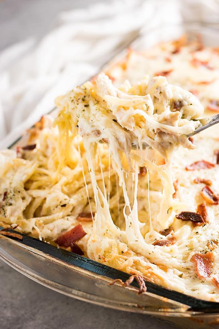 a close up of a casserole dish with cheese being lifted from the casserole