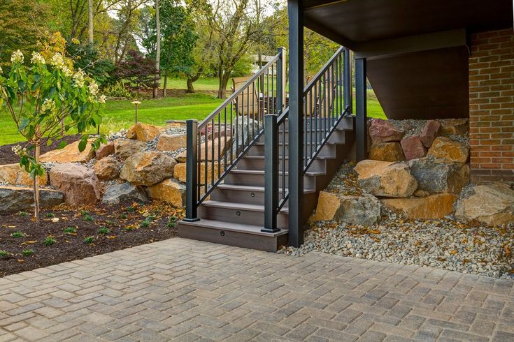 there is a stone wall and stairs leading to the front door, along with rocks on the ground