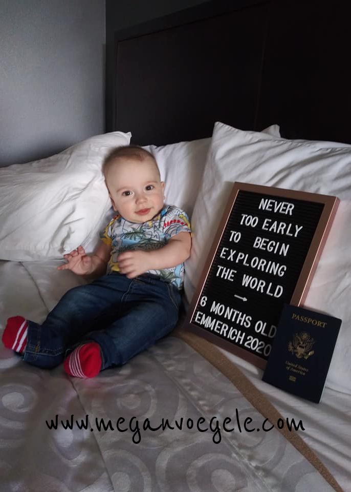 a baby sitting on top of a bed next to a sign