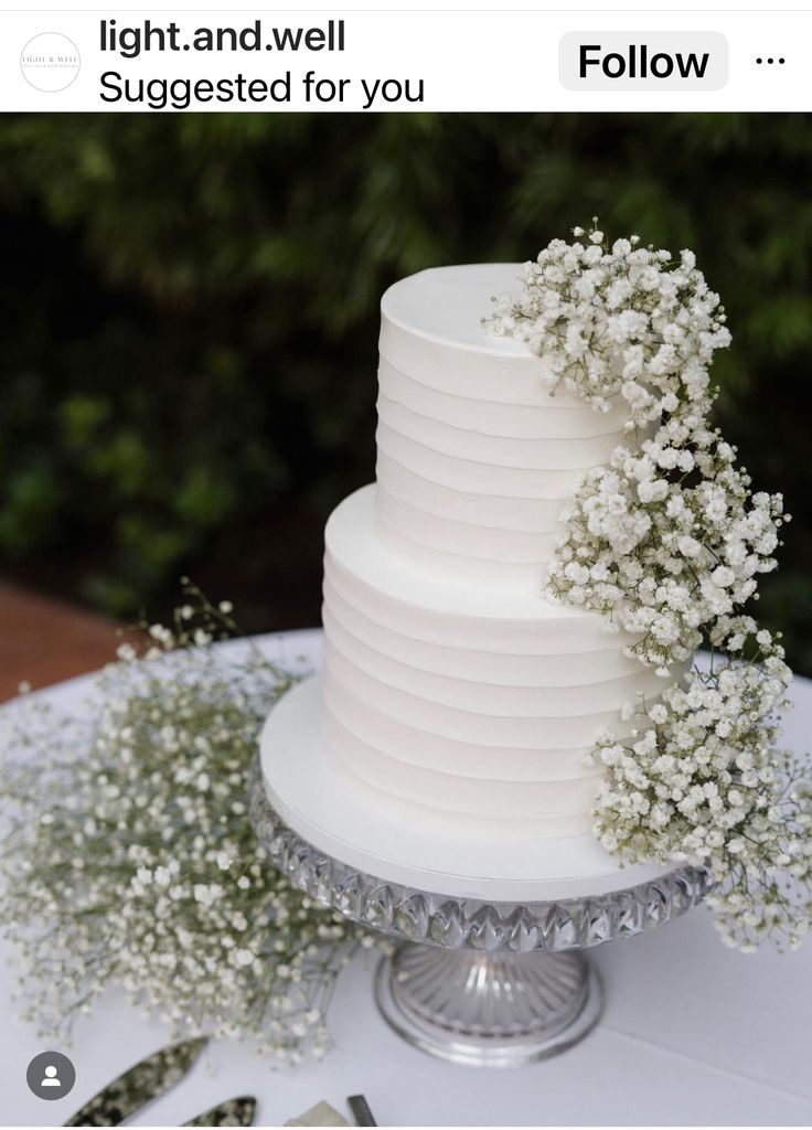 a white wedding cake with baby's breath flowers on the top and bottom tier