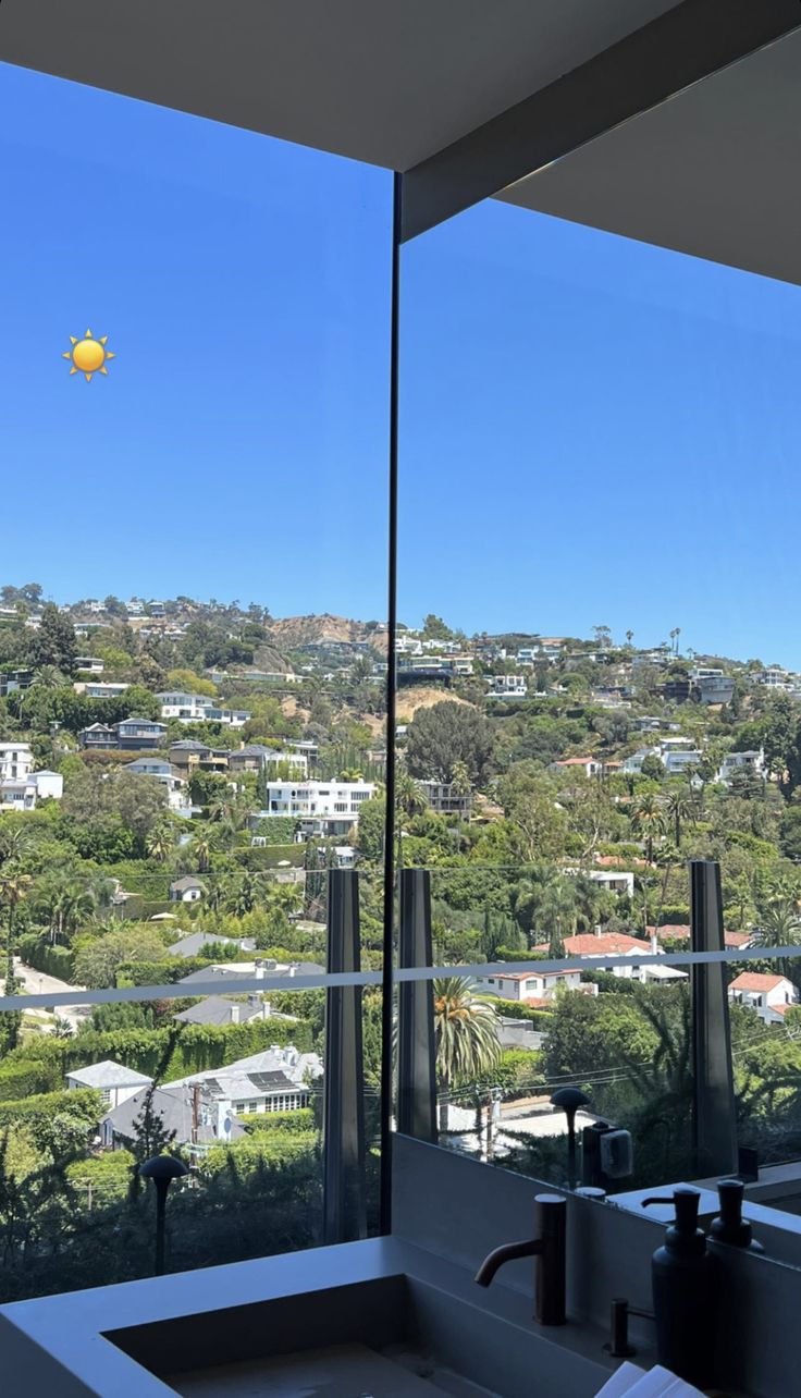 a bathroom sink sitting under a window next to a large window with a view of the city