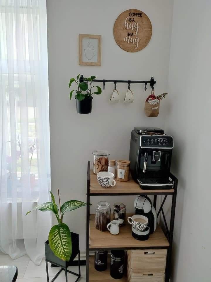 there is a coffee maker and some cups on the shelf in this room with two potted plants