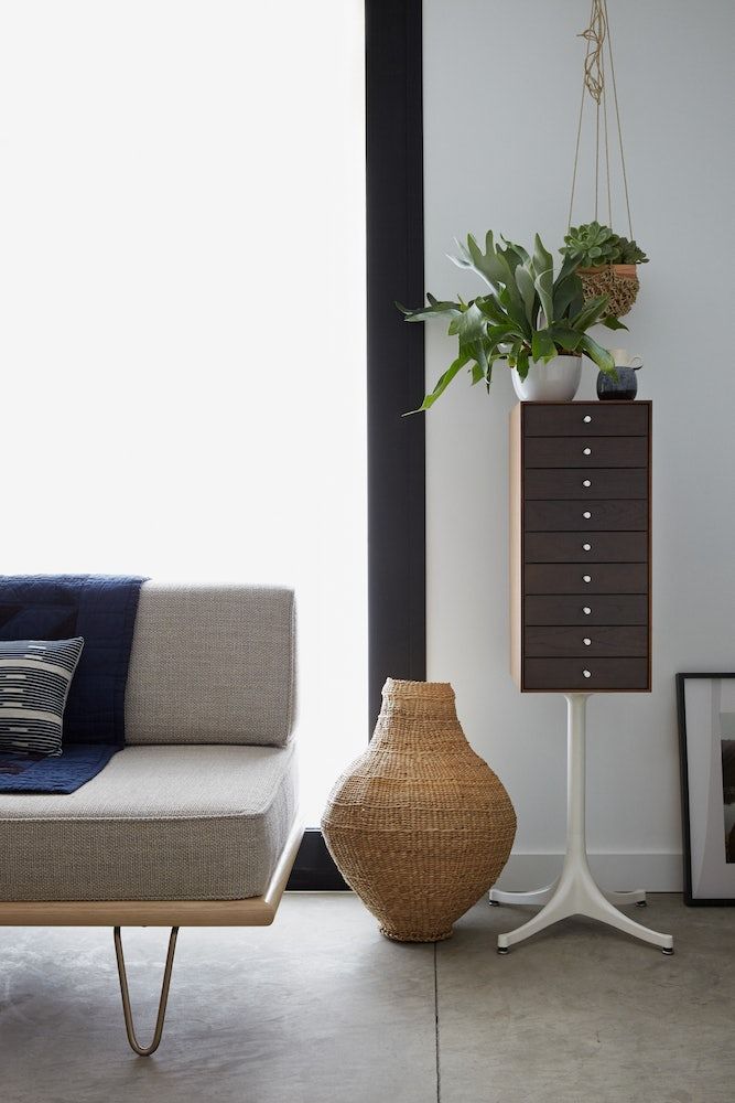 a living room with a couch, side table and potted plant