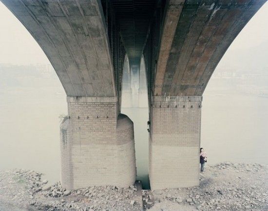 two people standing on the edge of a bridge