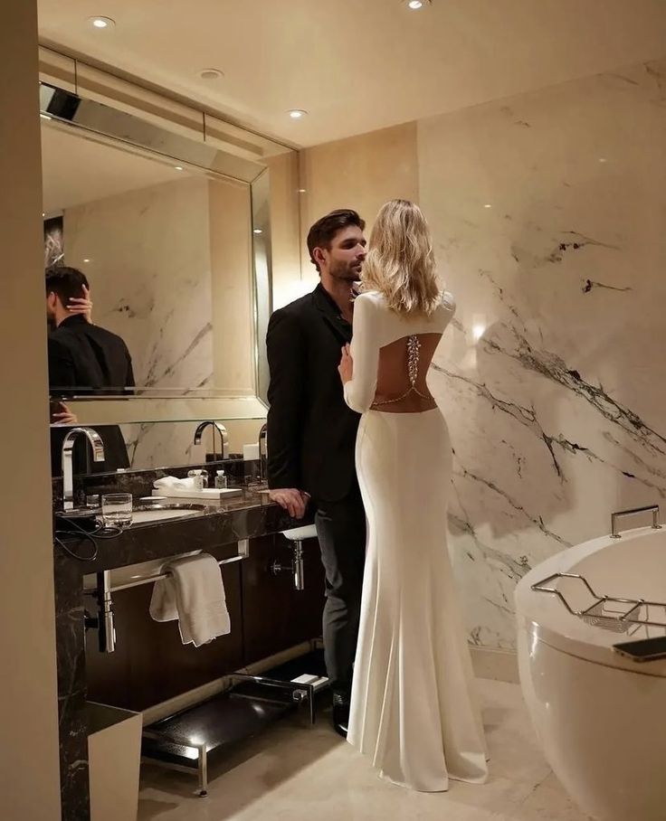 a man and woman are standing in front of a bathroom mirror looking at each other