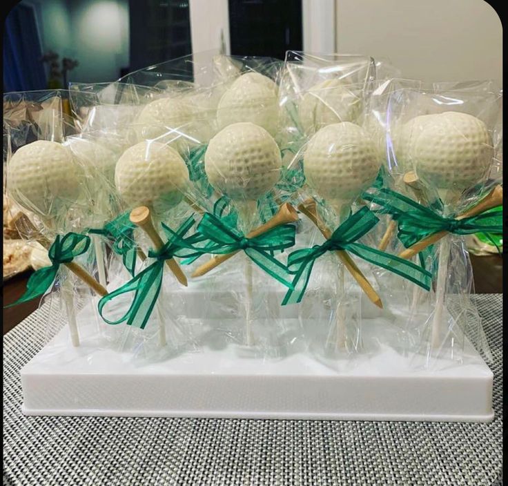 several golf balls are wrapped in plastic and tied with green ribbon on top of a table