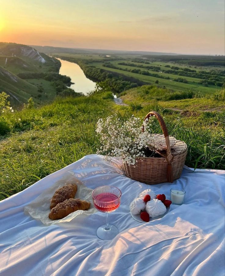 a picnic on the bank of a river with food and drinks in front of it