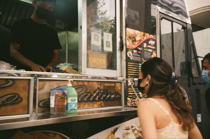 a woman standing in front of a food truck