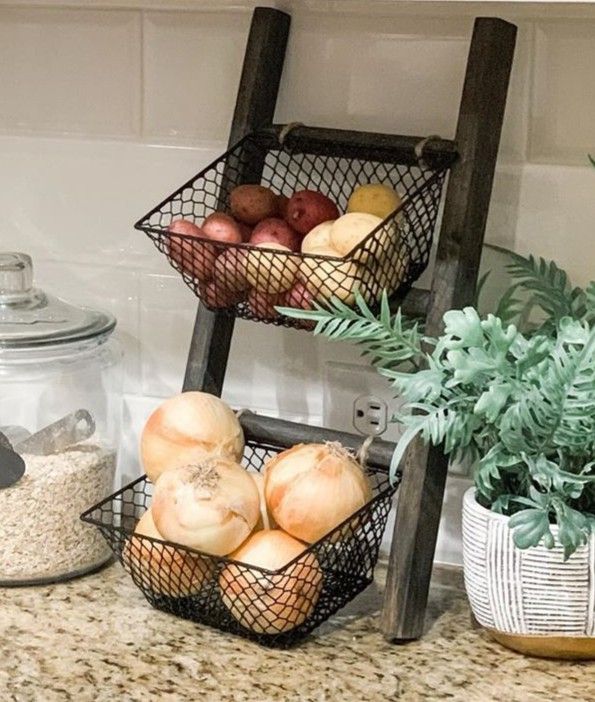 two metal baskets filled with fruit on top of a counter next to a potted plant