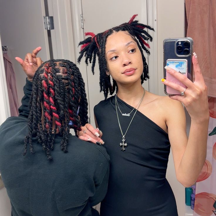 a woman taking a selfie in front of a mirror with another person holding a cell phone