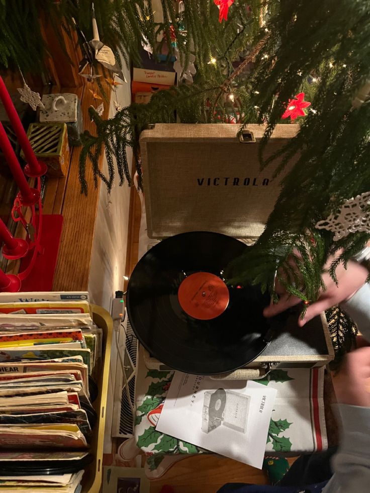 an old record player is sitting on the floor next to a christmas tree and records