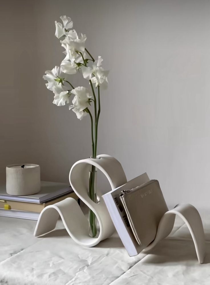 a vase with white flowers in it sitting on a table next to a stack of books