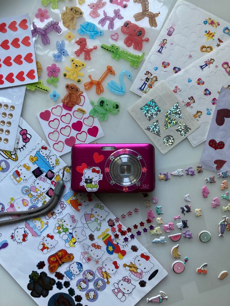 A old, pink digital camera decorated with colorful heart, hello kitty, gemstone, fruit stickers Digital Camera Aesthetic Stickers, Stickers On Digital Camera, Decorated Camera Aesthetic, Digital Camera With Stickers, Digital Camera Aesthetic Decorated, Decorate Digital Camera, Digital Camera Stickers, Digital Camera Decorated, Camera With Stickers