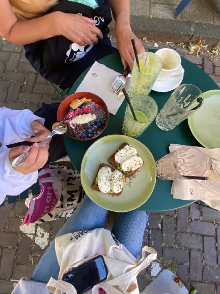 two people sitting at a table with plates and bowls of food in front of them