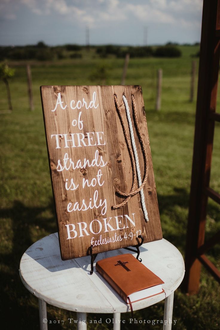 a wooden sign sitting on top of a white table next to a book and pen