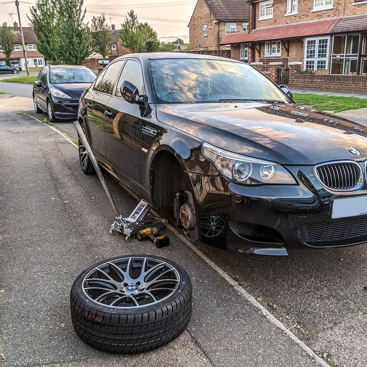 a black car is parked on the side of the road with a wheel attached to it