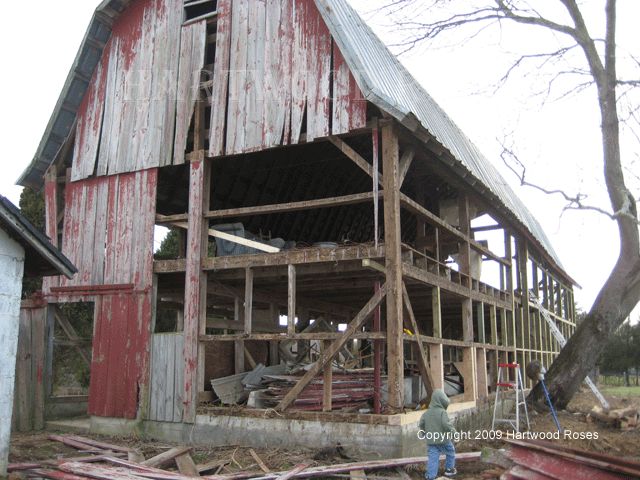 an old barn is being renovated with wood and other items in the yard around it