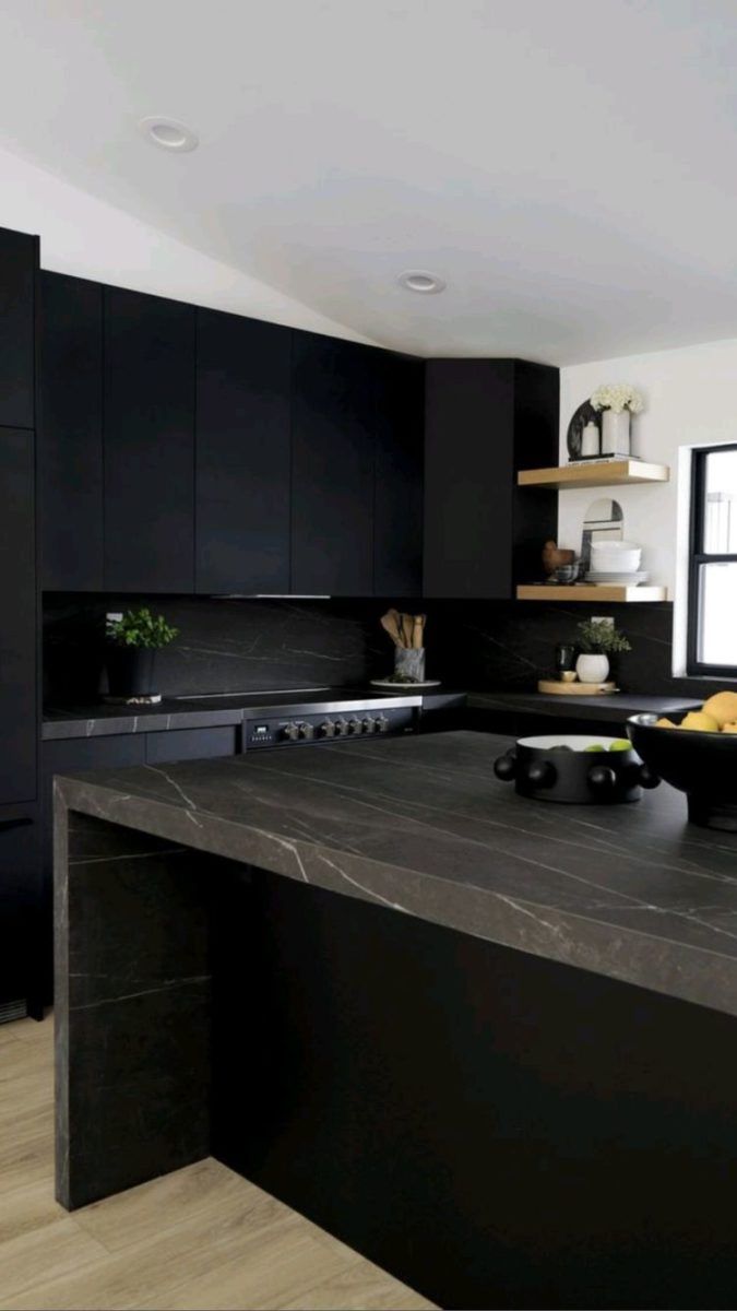 a large kitchen with black cabinets and counter tops is pictured in this image, there are fruit on the counter