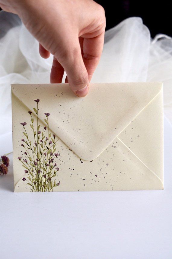 a person holding an envelope with flowers on it