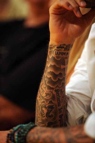 a man with a tattoo on his arm sitting at a table in front of other people