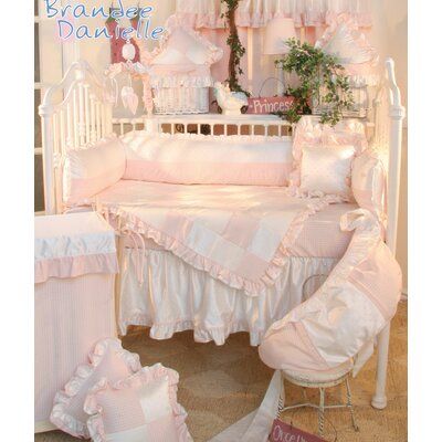 a white crib with pink bedding and pillows