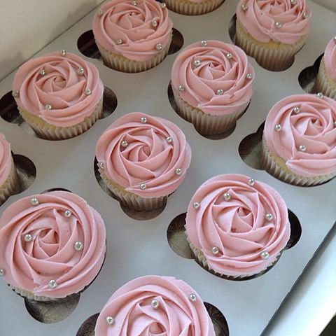 cupcakes with pink frosting in a white box