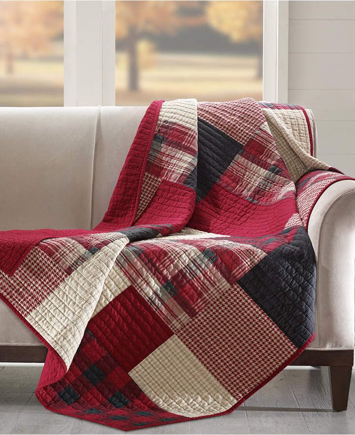 a couch with a red and black plaid blanket on it next to a white window