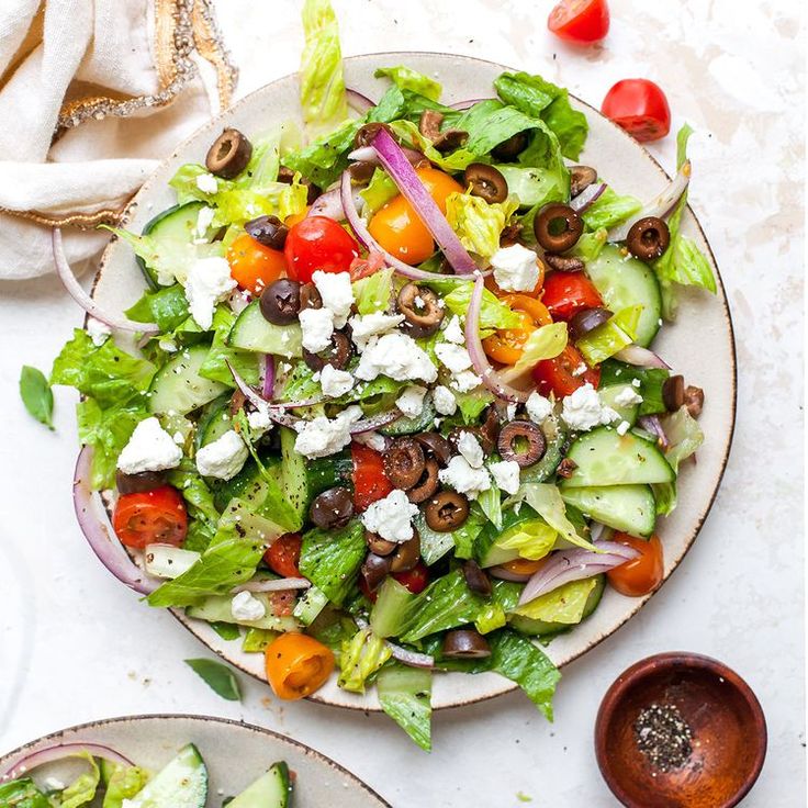 a salad with tomatoes, cucumbers, olives and feta cheese on it