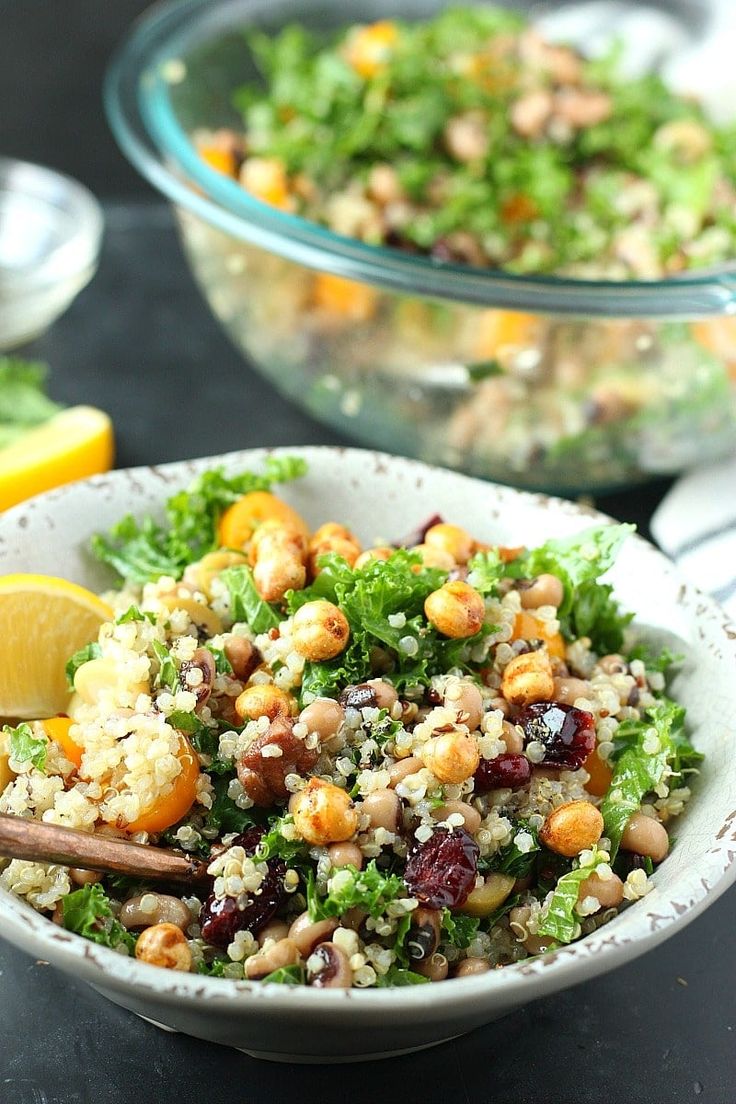 a white bowl filled with salad next to a lemon wedge