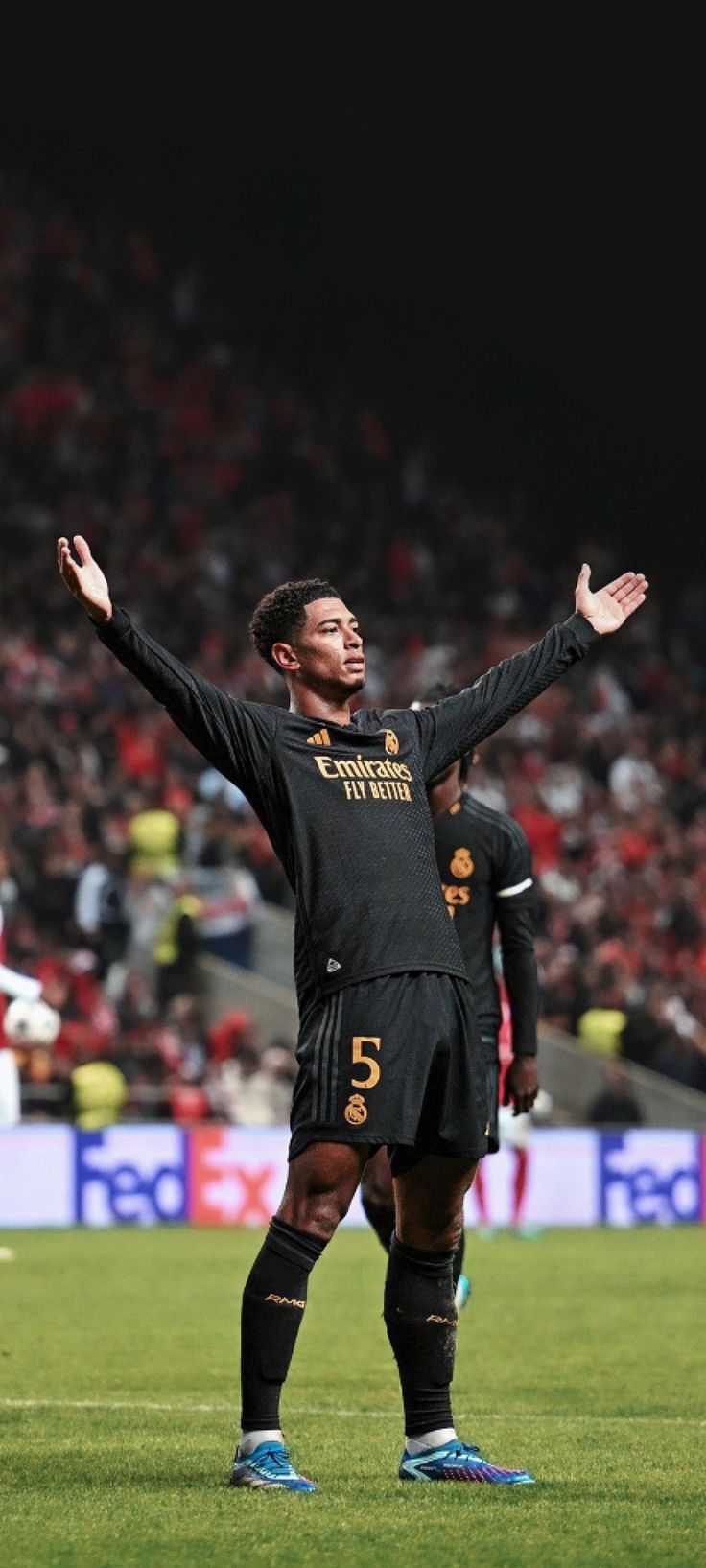 a man standing on top of a soccer field holding his arms up in the air