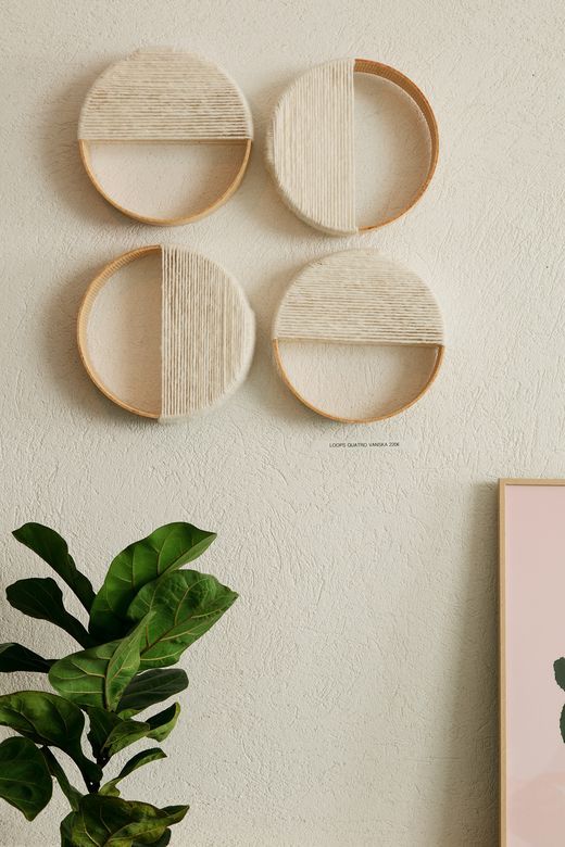 three circular wooden shelves on the wall above a potted plant and a framed photograph