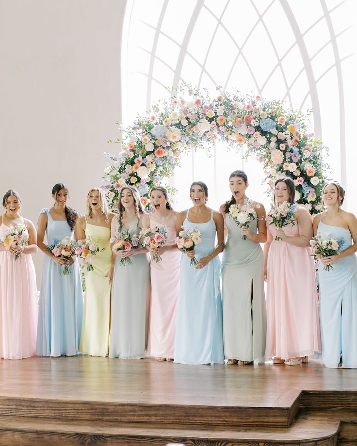 a group of women standing next to each other on top of a wooden floor holding bouquets