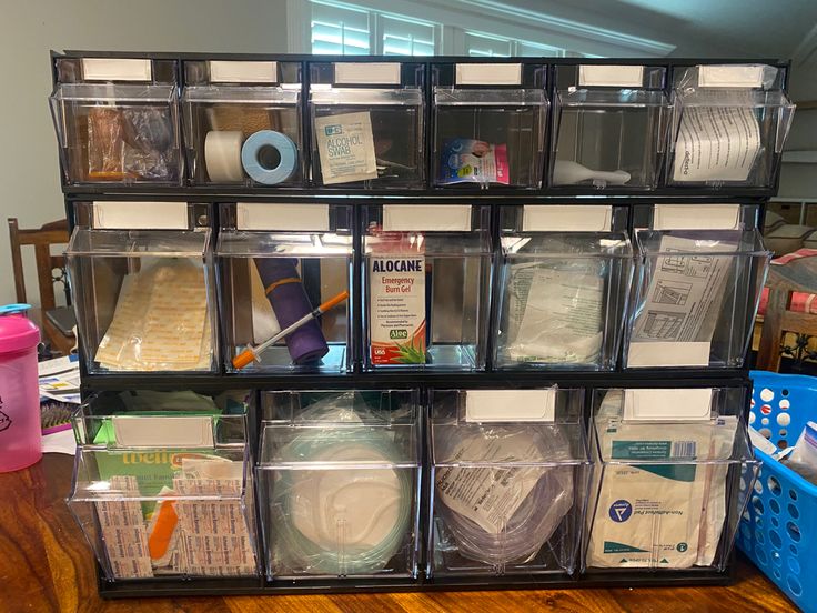 a stack of plastic bins filled with lots of crafting supplies on top of a wooden table