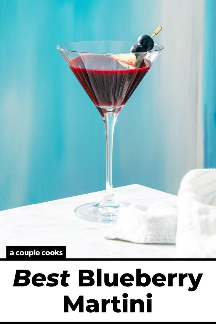 the best blueberry martini recipe is in a coupe glass with an olive garnish