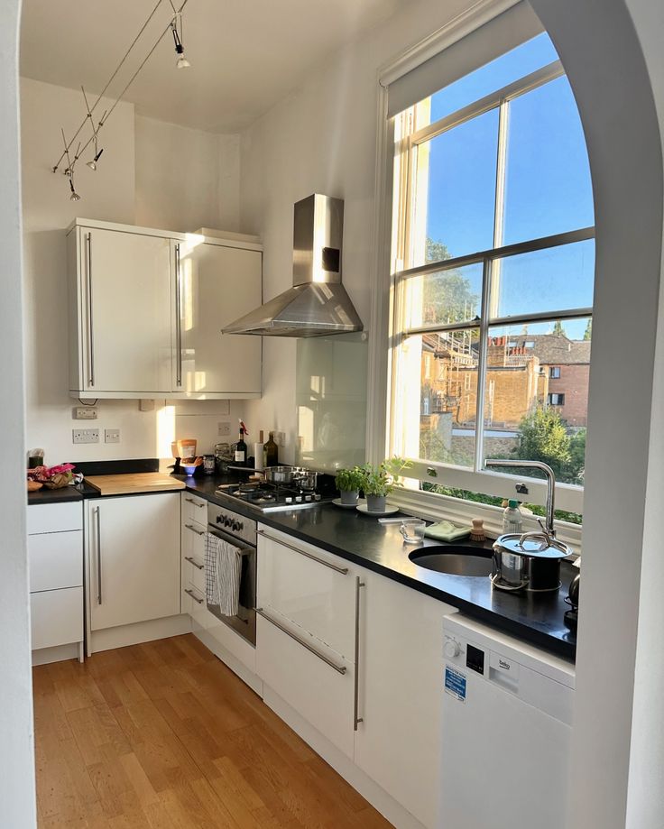 a kitchen with white cabinets and black counter tops is seen through an arch in the wall