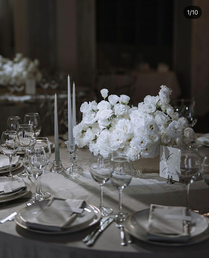 the table is set with white flowers and silverware