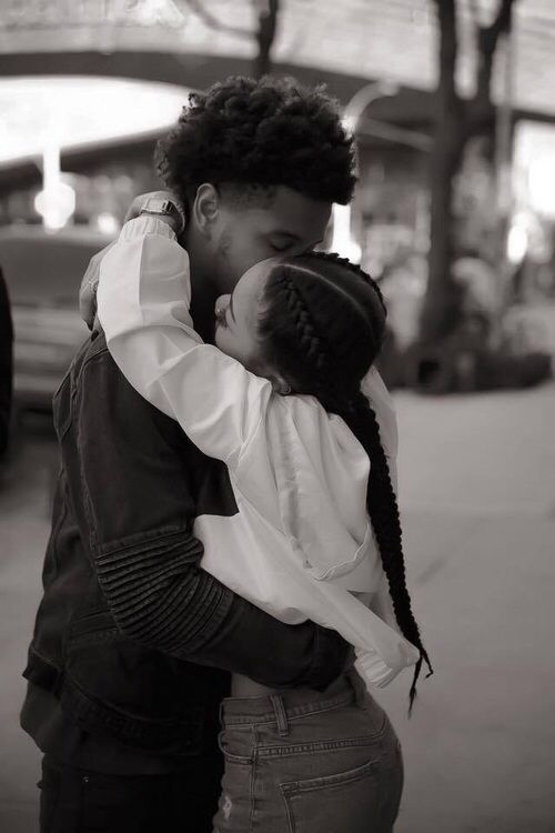 a man and woman embracing each other on the street with an instagramr above them