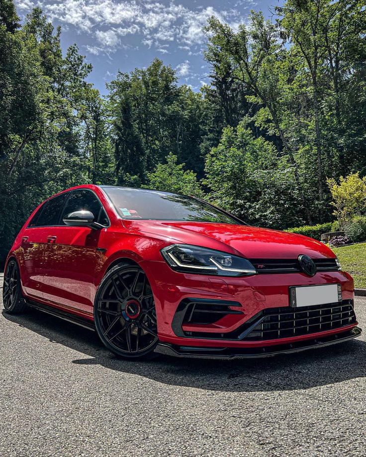 a red volkswagen golf gtr parked in front of some trees