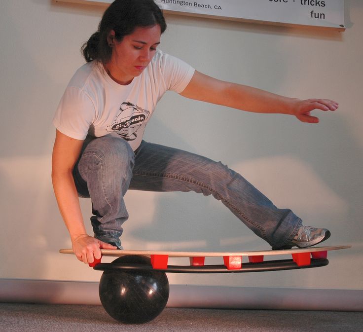 a person riding a skateboard on top of a ball in front of a wall