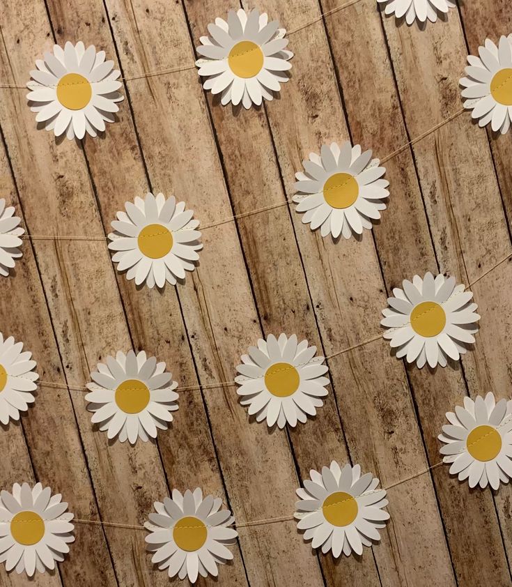 many white flowers are placed on a wooden surface with string attached to them and yellow dots in the middle