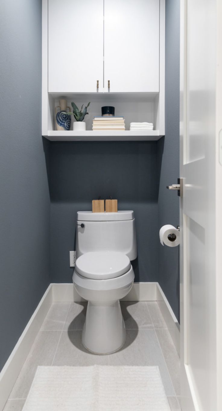 a white toilet sitting in a bathroom next to a cabinet with books on top of it