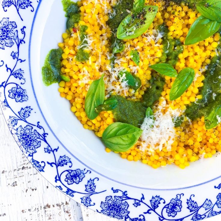 a white and blue plate topped with corn, spinach and parmesan cheese