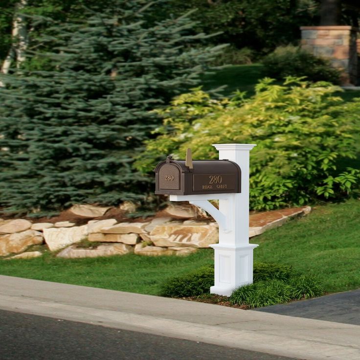 a white mailbox sitting on the side of a road next to a lush green field