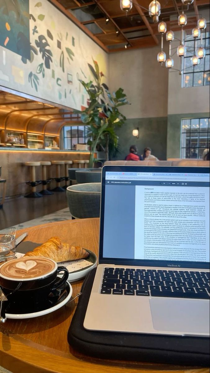 an open laptop computer sitting on top of a wooden table next to a cup of coffee